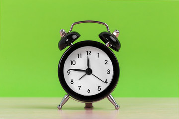 Vintage black alarm clock on a bright green background