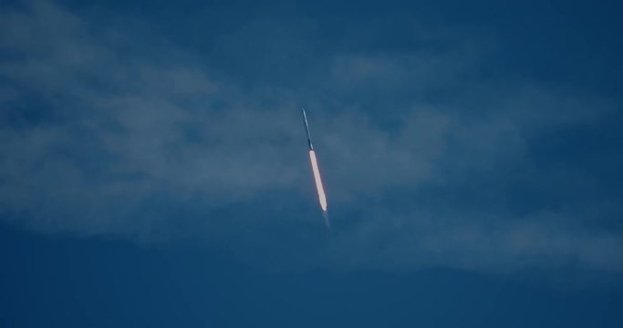 Rocket missile flying through clouds with exhaust flames and smoke in 4K.