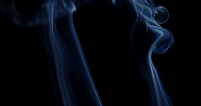 Bluish cloud of smoke rising against a black background in slow motion