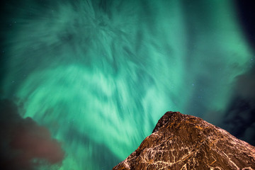 Aurora Borealis (Northern lights) dancing on steep mountain in sky