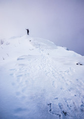 Naklejka na ściany i meble Man stand pointing on snow steep ridge