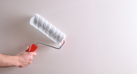 Hand with roller on white wall