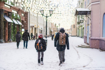 Obraz premium dwaj chłopcy chodzą po ulicach miasta w sezonie zimowym pod opadami śniegu