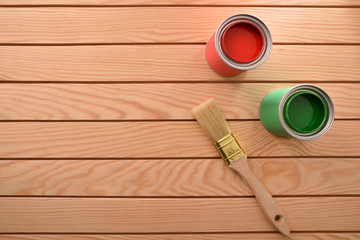 Two paint cans and brush on wooden slats top view