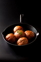 Food Homemade raw organic spicy meatball in iron cast on black background
