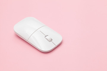 White wireless optical mouse with a wheel on a pink background. Modern concept for the Internet web...