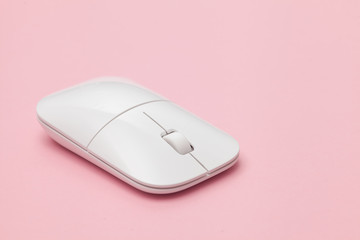 White wireless optical mouse with a wheel on a pink background. Modern concept for the Internet web...