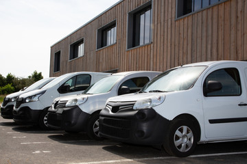 Row white delivery service van small trucks park front of factory warehouse distribution plant
