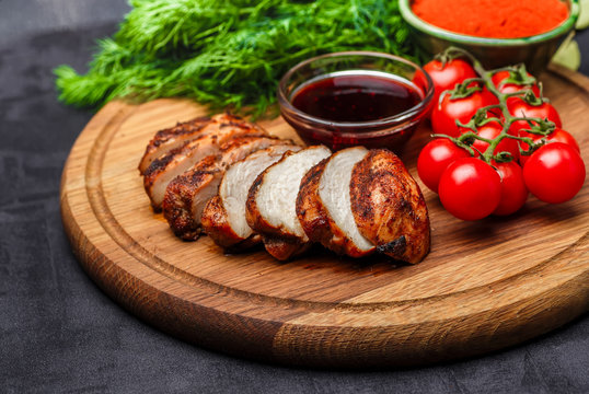 whole and sliced chicken breast with spices on a stone board, top view copy