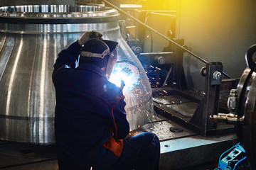 Industrial Worker labourer at the factory welding steel