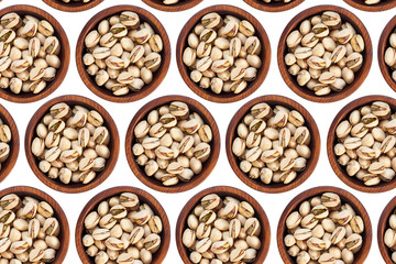 Unpeeled pistachios in a wooden cedar plate on a white isolated background. Row of bowls with pistachio nuts, top view. Unpeeled pistachios pattern