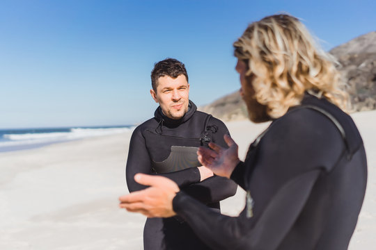 surf instructor with a student on the ocean. Surfer in a wet suit with a training board. Nazare, Portugal.