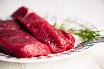 fresh raw beef steak on a plate on a wooden background