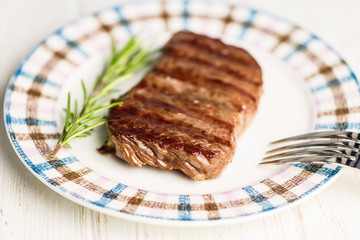 medium grilled beef steak grilled on a plate with fork and knife