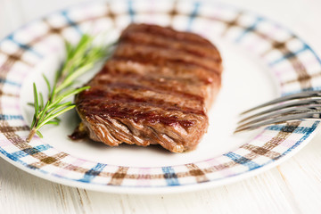 medium grilled beef steak grilled on a plate with fork and knife
