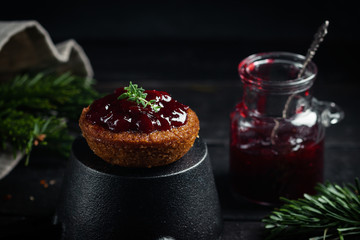 Little chocolate homemade muffin garnished with cherry jam. Dark moody style. Selective focus