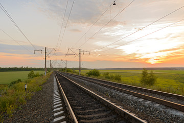 Fototapeta na wymiar empty railroad with pillars in the open field at sunset