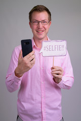 Young happy businessman holding phone with selfie paper sign