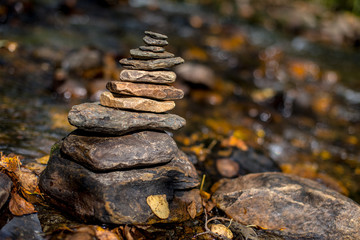 Stone pyramid on a blurred background of a mountain river in autumn
