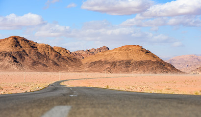 Kings highway, beautiful curvy road running through the Wadi Rum desert with rocky mountains in the distance in Jordan.