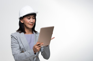 Beautiful Asian Smart Architect Engineer 50s 60s years old woman in white hard hat helmet hold tablet iot, portrait studio lighting gray background copy space, concept aging society woman can do