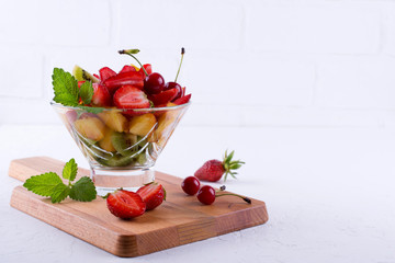 Colorful fruit salad in the glass bowl. Strawberries, kiwis and apricots