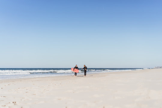 surf instructor with a student on the ocean. Surfer in a wet suit with a training board. Nazare, Portugal.