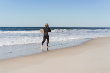 surfer with flippers and a bodyboard in a hydro suit on the ocean shore