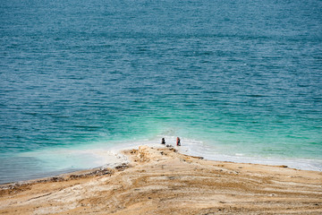 Fototapeta na wymiar Stunning aerial view of the Dead Sea with some people strolling on the shore, Israel.