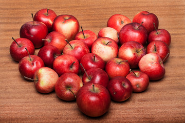 Fototapeta na wymiar Organic apples, apple in a heart shape on wooden table