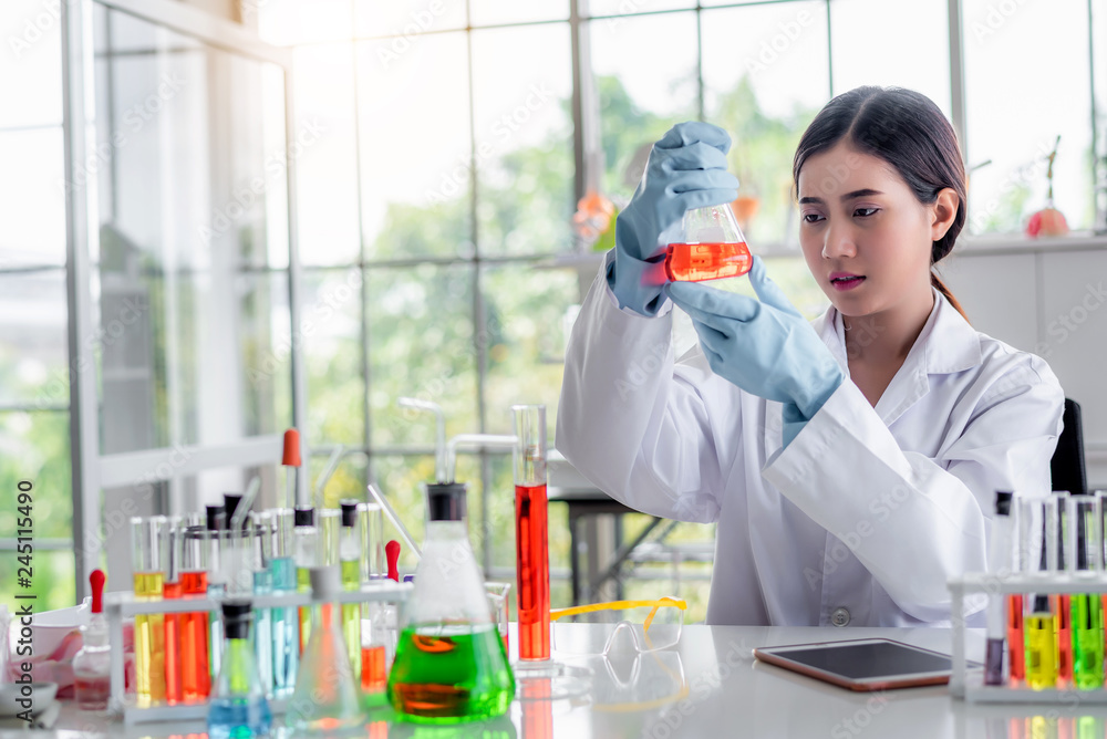 Poster attractive scientist looking chemical sample in flask at laboratory with lab glassware background. s