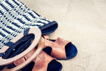Vintage summer wicker straw beach bag and leather sandals on the seashore of Catania, Sicily, Italy.