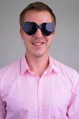 Face of young happy businessman smiling while wearing heart shape sunglasses