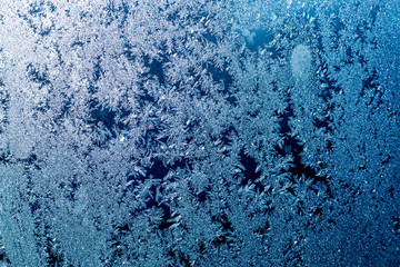 Fototapeta na wymiar Ice patterns on glass, frost on a winter window, fancy patterns of winter.