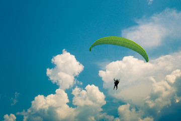 Two people are flying on a paraglider in the sky. Toned