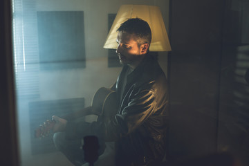 Guy handsome playing guitar. Musician playing acoustic guitar at home.