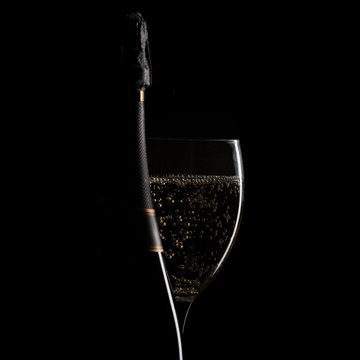 bottle and glass of sparkling wine, silhouette on black background, center