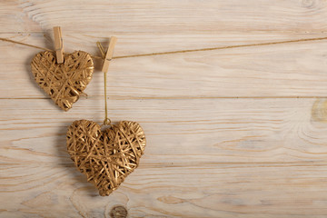 Happy Valentine's Day! Decorative wicker hearts of gold color on a light wooden background.