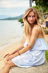 Fototapeta na wymiar Pretty girl at beach, sitting on wall