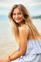 Fototapeta na wymiar Smiling young blond woman at beach, portrait
