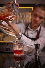 Professional bartender prepairing orange cocktail 