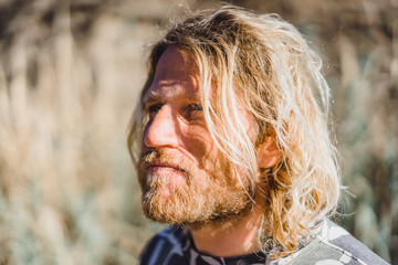 man with long white hair, in a baseball cap, looking into the distance, a portrait. surfer.