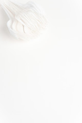 A bunch of disposable single-use white plastic forks set on a seamless white paper background.