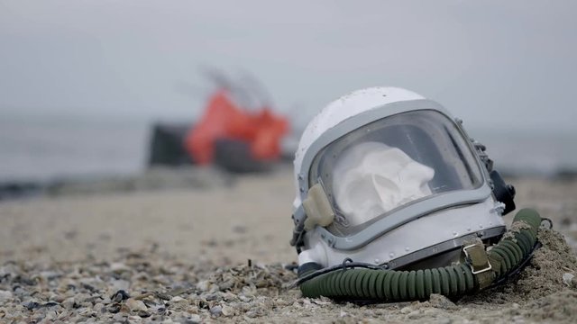 dead astronaut on the planet. The skull from the head in the helmet lies on the sand by the sea. Troubled by accident.