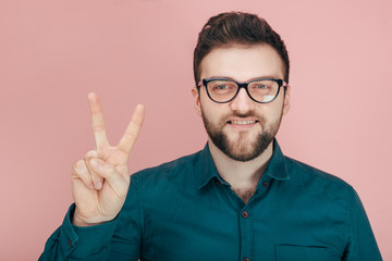 Naklejka premium a man with a beard in glasses and a shirt shows two on his fingers