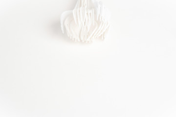 A bunch of disposable single-use white plastic forks set on a seamless white paper background.