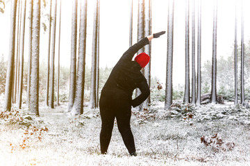 Plus size woman doing exercises in winter forest. Outdoor fitness.