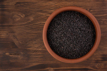 bowl of black wild rice on wooden table background, top view