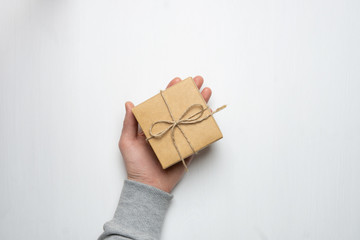 young man's hand holds a gift in a box on a white background