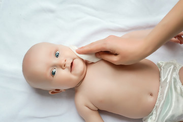 Hygiene - young mom wiping the baby skin body and leg with wet wipes carefully on white background....